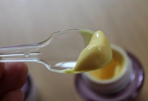 Cận cảnh texture kem màu vàng lỏng mượt, thẩm thấu nhanh, không gây mụn của kem dưỡng tái tạo da DHC Q cream